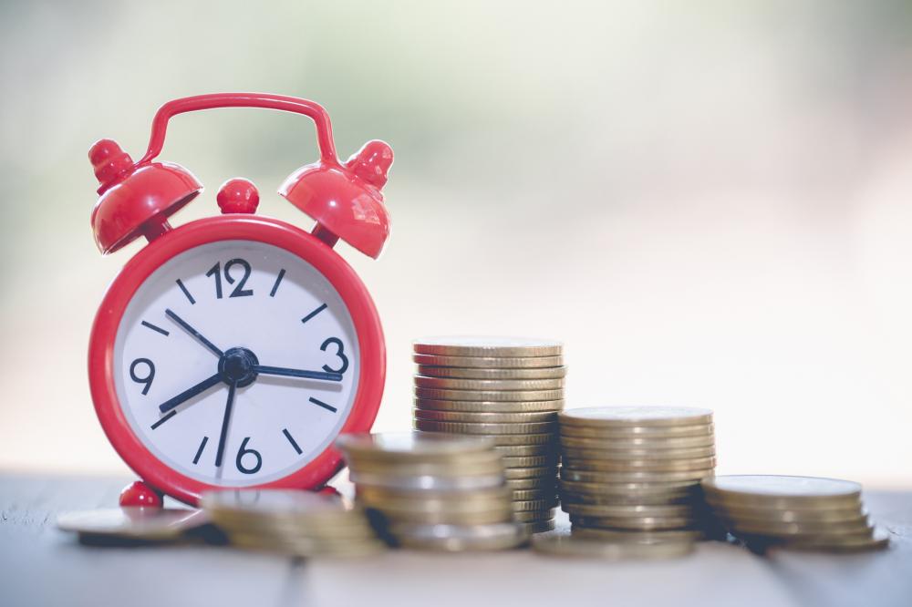 red clock next to stacks of coins