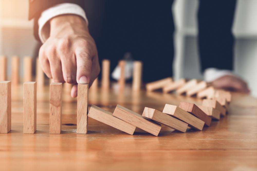 businessman stops dominoes from falling
