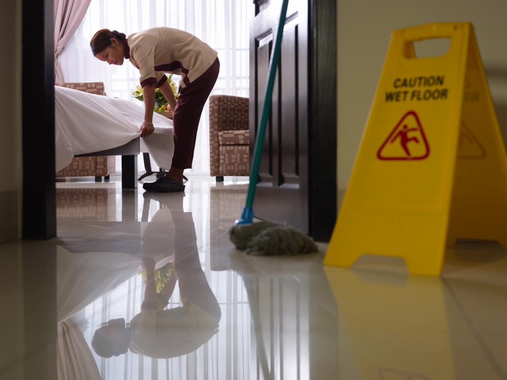 housekeeper cleans a hotel room with the door open