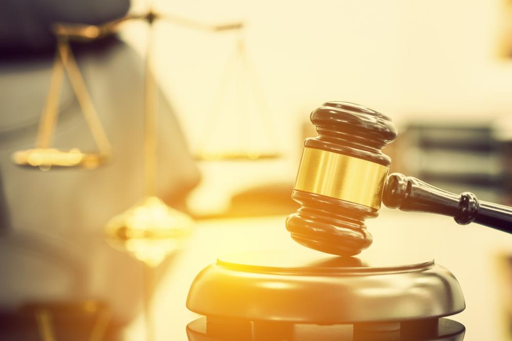 Wooden judge gavel with a blurred brass scale of justice behind
