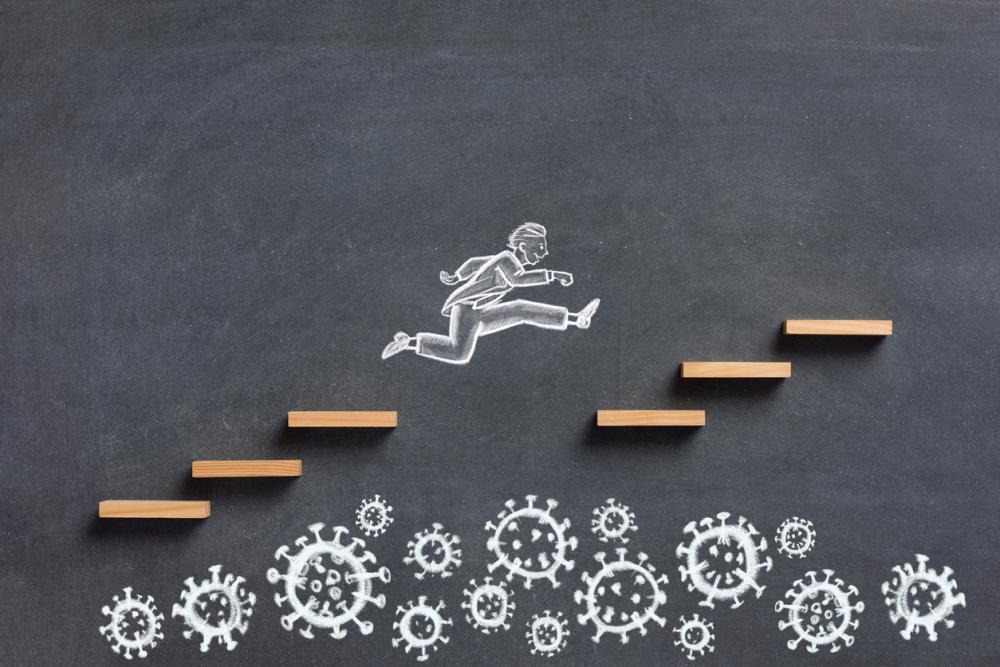 chalkboard drawing: businessman leaps over germs to continue on path