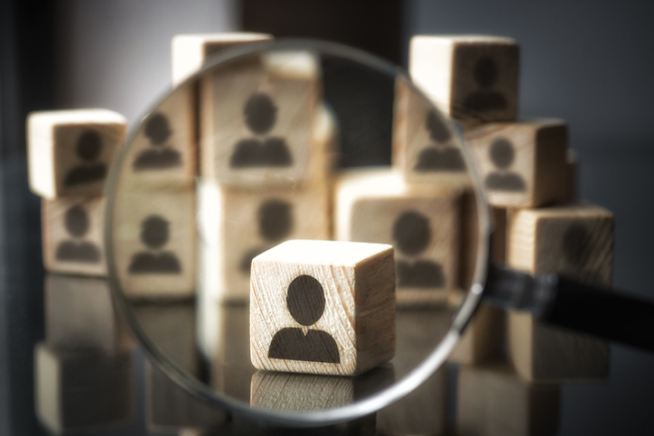 Businessman silhouette focused on by magnifying glass