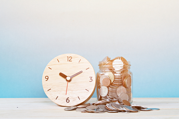 wooden clock next to jar full of coins