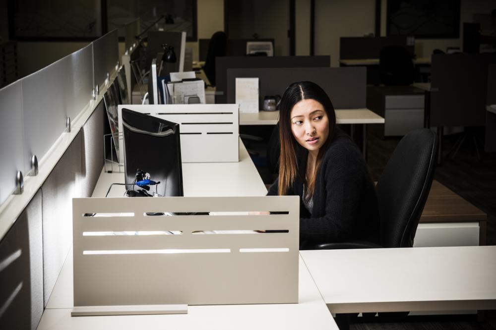 A low key shot of a woman in an office at night accessing a computer.