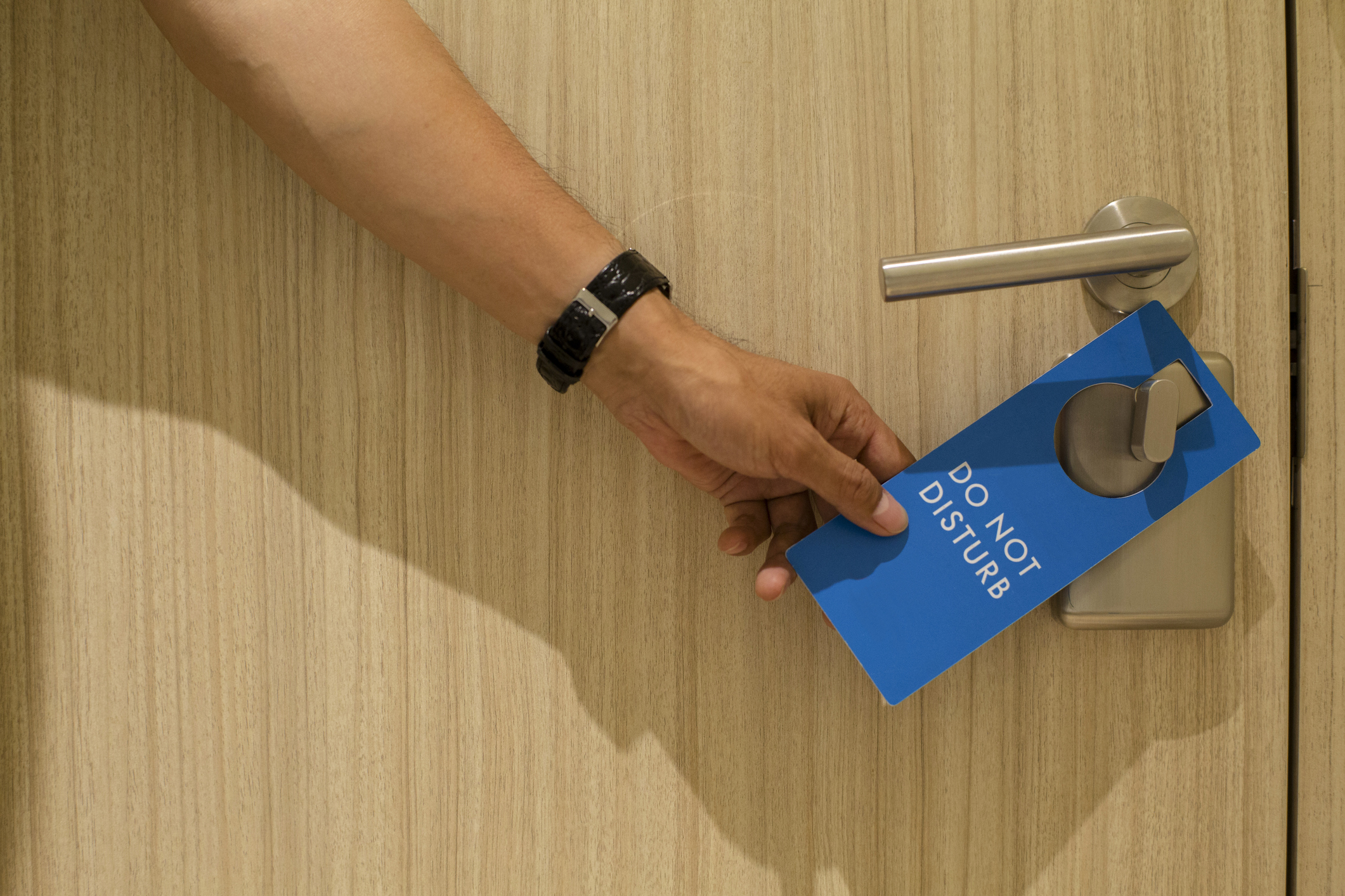 hand placing 'Do Not Disturb' sign onto hotel room door