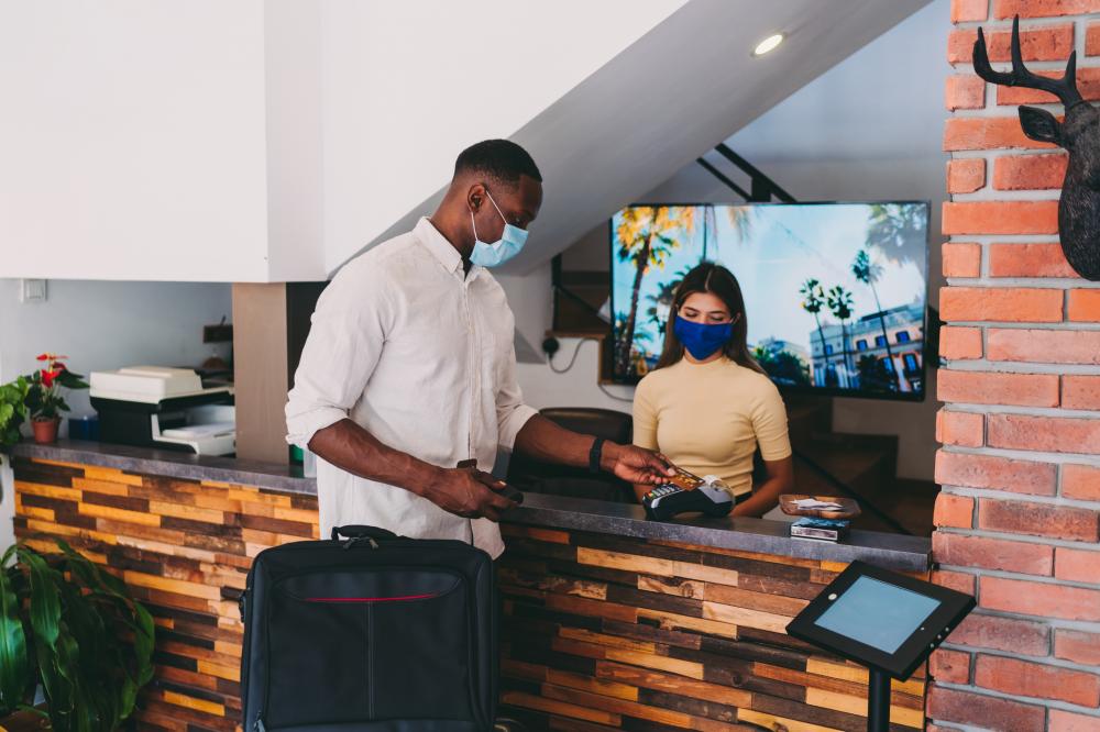 Latin American Maid working at a hotel doing room service wearing a facemask and pushing a cart â COVID-19 pandemic lifestyle concepts